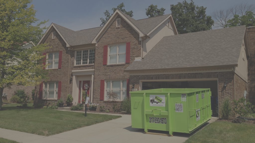 A bright green Bin There Dump That dumpster placed on a residential driveway in Indianapolis, IN, ready for general junk removal.