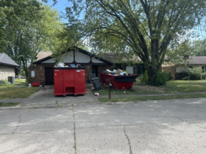 A house with two large red dumpsters filled with various junk items in the driveway, provided by Z & Z Services in Indianapolis, IN.