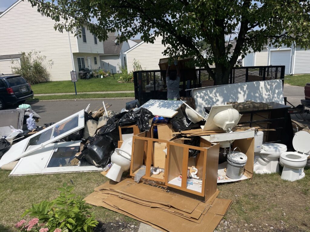 A large pile of household junk including toilets, cabinets, and doors on a lawn for Junk Fellas LLC removal in Columbus, OH.