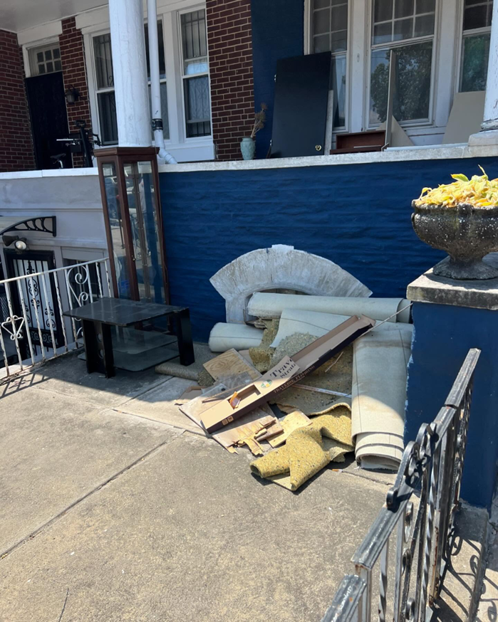 A pile of household junk and debris on a porch, ready for removal by JUNK BOX LLC in Philadelphia, PA.