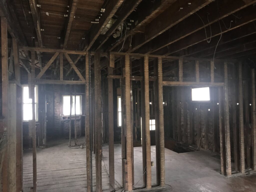 An interior view of a house after demolition, showing exposed studs and floorboards by Junk Removal and More LLC in Columbus, OH.