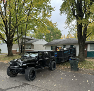 A black Jeep pulling a junk removal trailer filled with items for Precision Junk Removal in Columbus, OH.