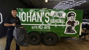 Johan holding a large trash bag, ready to load it into his junk removal trailer for Johan's Junk Removal in San Diego, CA.