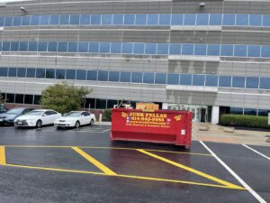 A red Junk Fellas LLC dumpster parked in a commercial parking lot for junk removal in Columbus, OH.