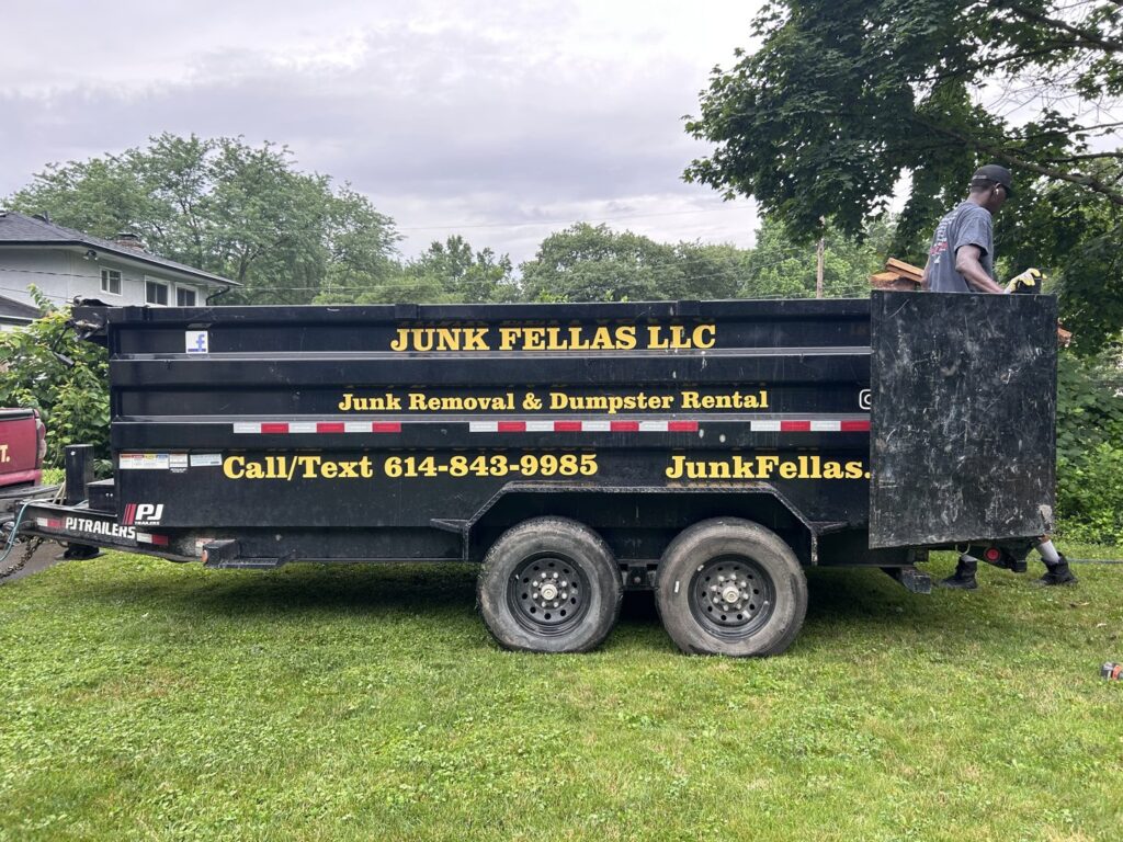 A black Junk Fellas LLC dump trailer with a worker on site, ready for junk removal in Columbus, OH.