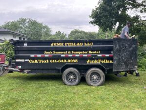 A black Junk Fellas LLC dump trailer with a worker on site, ready for junk removal in Columbus, OH.