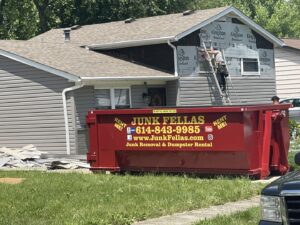 A red Junk Fellas LLC dumpster rental in front of a house undergoing renovation in Columbus, OH.