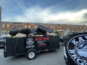 A trailer filled with various junk items, branded with Kay's Brothers Junk Removal, on a street in Philadelphia, PA.