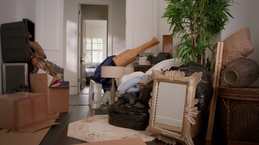Junk King employees loading a large brown recliner and other furniture into a junk removal truck in Austin, TX