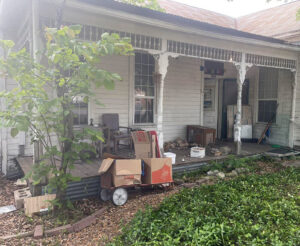 Various items and junk piled on a house porch, awaiting removal by G.I. HAUL in Austin, TX.