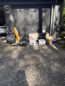 Various bags of trash and junk piled on a driveway, awaiting pickup by Clutch City Junk Removal in Tomball, TX.