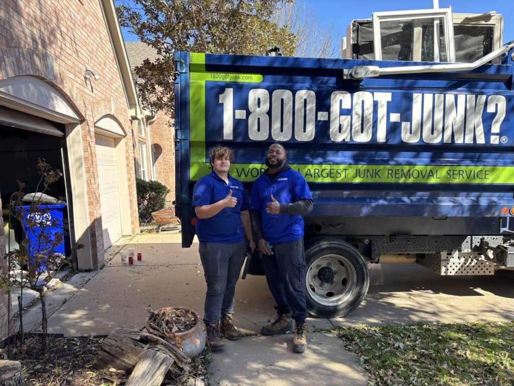 Two 1-800-GOT-JUNK? crew members giving thumbs up in front of their truck with yard debris in Fort Worth, TX.