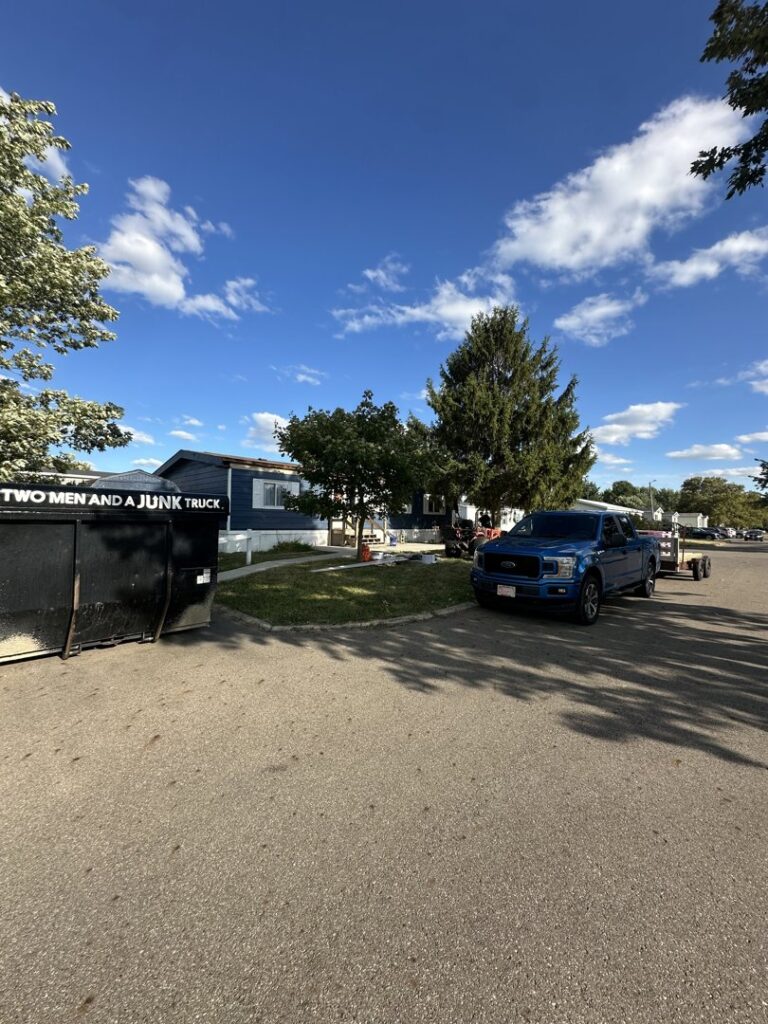 A branded junk removal dumpster truck from Two Men and a Junk Truck parked in a residential area in Columbus, OH.