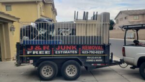 A branded J & R Junk Removal trailer filled with various household junk and debris in Phoenix, AZ, ready for hauling.