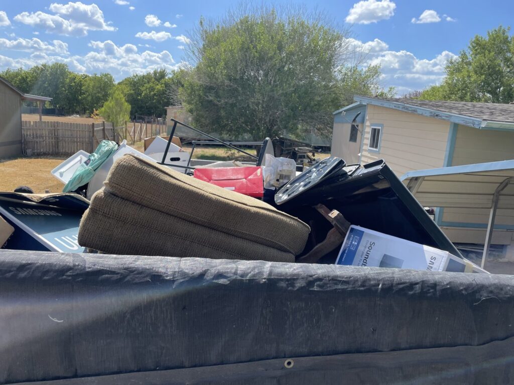 A junk removal trailer filled with household items like couch cushions and electronics by Firefighter Junk Removal in Austin, TX.