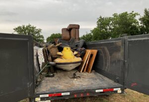 A large junk removal trailer filled with various items including furniture and a jet ski by Junkie 4 Jesus Junk Removal in Austin, TX