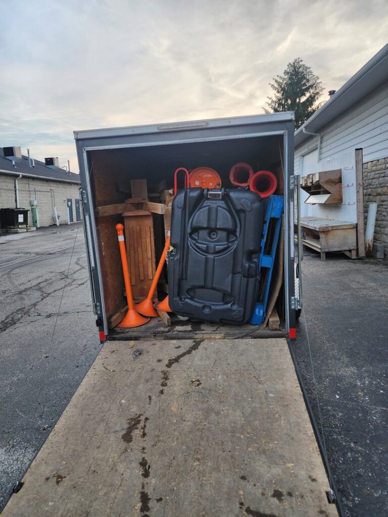 A Master Junkers trailer loaded with various items, including orange cones and a large container, in Powell, OH.