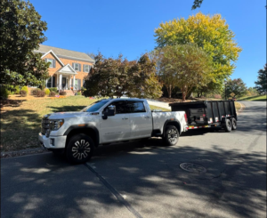 A white pickup truck with a black dump trailer parked on a residential street, ready for junk removal by Junkjet in Charlotte, NC.