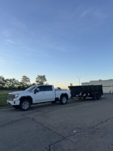 A white pickup truck with an empty dump trailer parked on a street by Junkjet in Charlotte, NC.