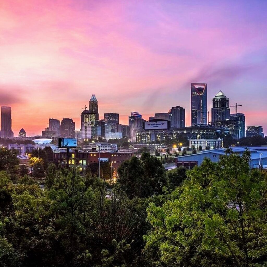 A SQS Junk Removal truck parked next to a pile of wood debris at a job site in Charlotte, NC.