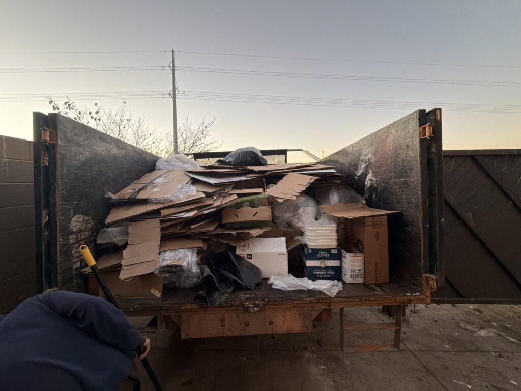 The back of a Junk Out Boyz LLC truck loaded with cardboard boxes and trash bags after a junk removal service in Austin, TX.