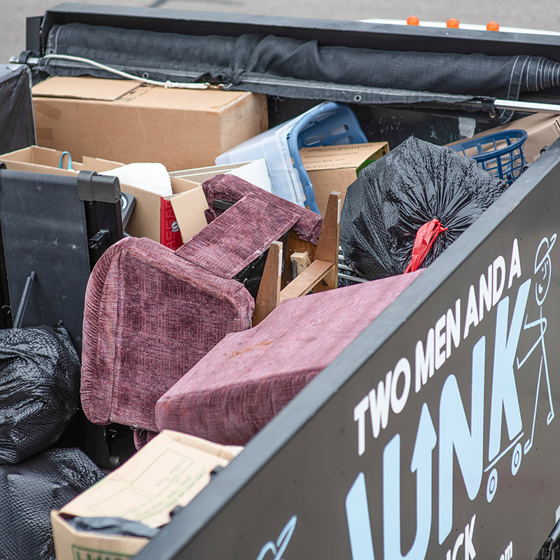 A close-up of a Two Men and a Junk Truck vehicle loaded with furniture, boxes, and trash bags after a job in Columbus, OH.