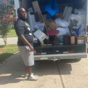 A Top Notch Junk Removal professional standing by a truck loaded with various items for removal in Houston, TX.