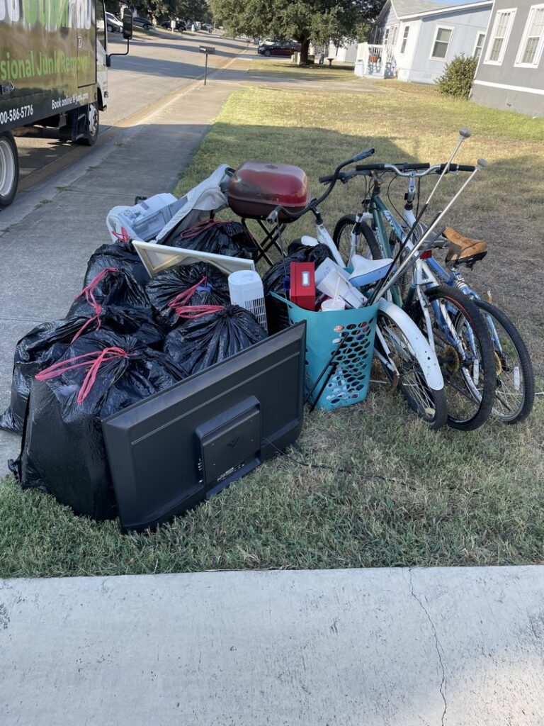 The back of a 1-800-JUNKPRO junk removal truck loaded with trash bags, boxes, and wood debris in Austin, TX.
