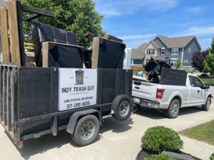 A junk removal truck and trailer loaded with furniture and debris by Indy Trash Guy in Fortville, IN.