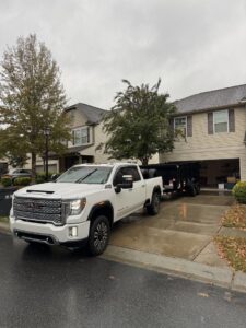 A white pickup truck with an empty dump trailer parked in a residential area, ready for junk removal by Junkjet in Charlotte, NC.