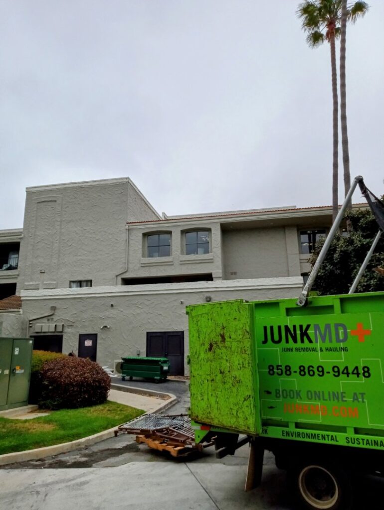 A JunkMD truck parked outside a building, collecting metal debris and junk in San Diego, CA.