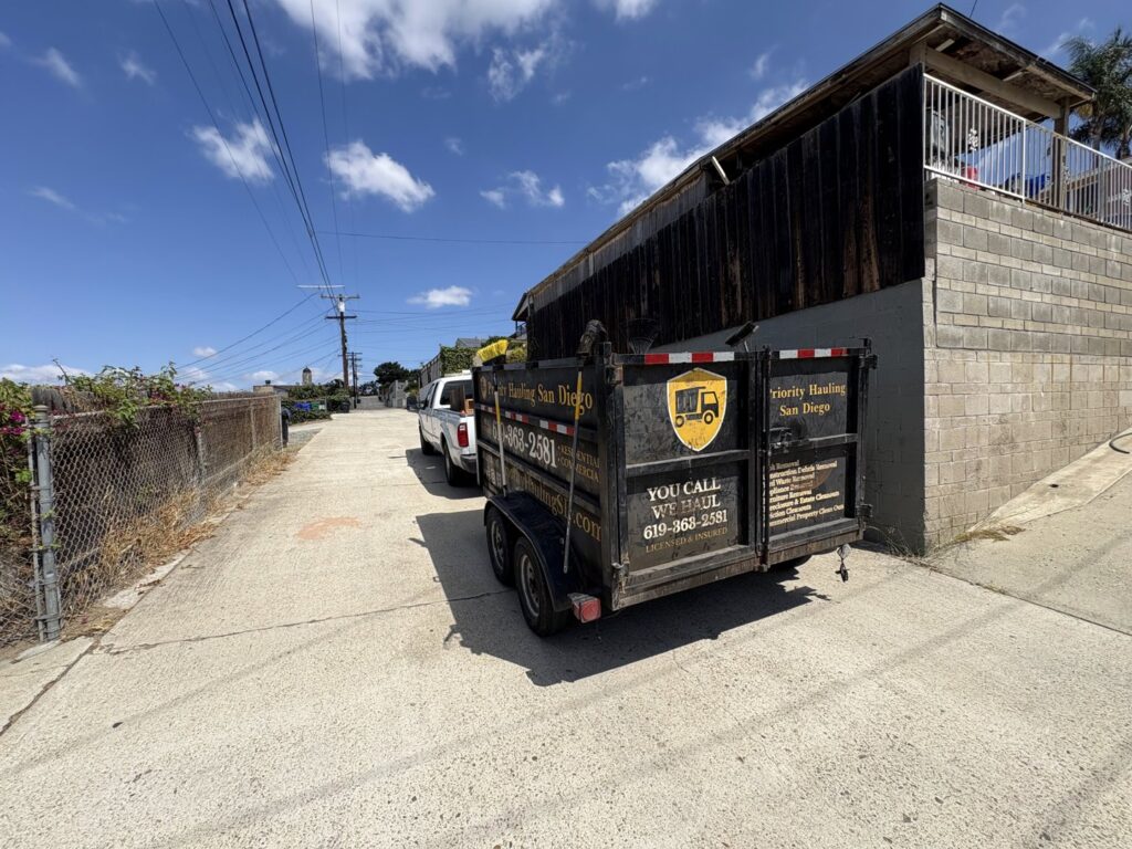 An interior view of a room with an old stove, buckets, and renovation debris, ready for removal by Priority Hauling and Junk Removal San Diego.