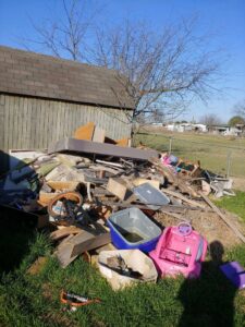 A large pile of miscellaneous junk and debris in a backyard, awaiting removal by Haulaway Junk Removal Service, LLC in Dallas, TX.