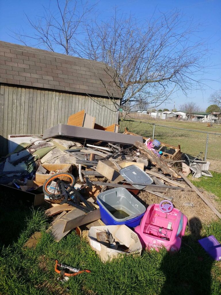 A large pile of miscellaneous junk and debris in a backyard, awaiting removal by Haulaway Junk Removal Service, LLC in Dallas, TX.