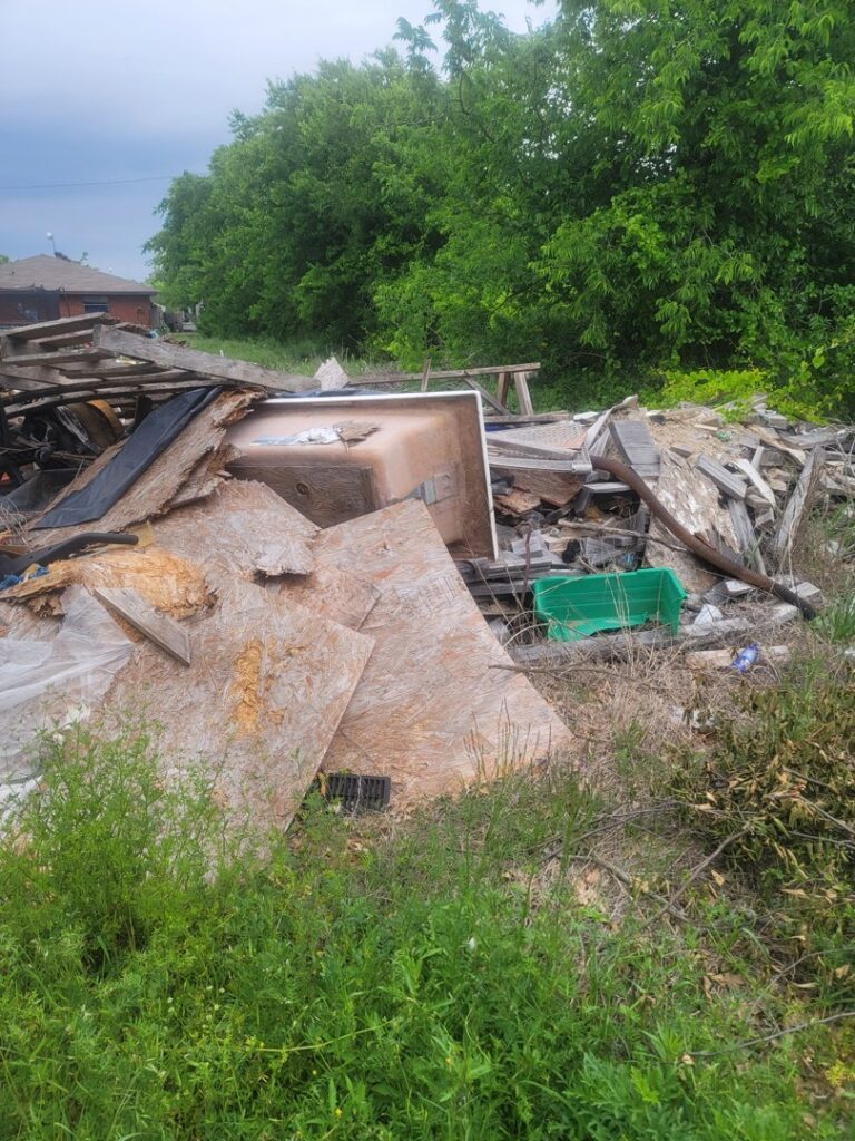 A large, overgrown pile of mixed debris, including wood and an old bathtub, requiring removal by NTX Haul Away Junk Removal in Fort Worth, TX.