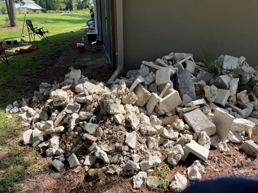 A large pile of concrete and cinder block debris next to a house, ready for removal by DUMP 4 U Hauling in Jacksonville, FL
