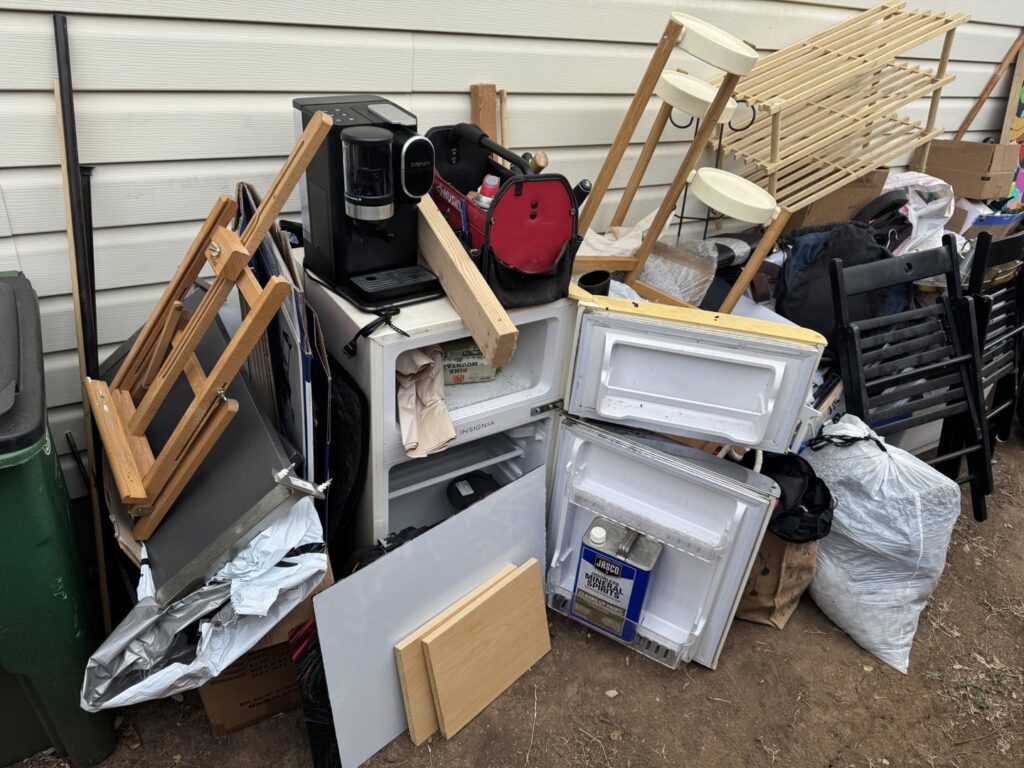 A large pile of various household junk, including a mini-fridge and chairs, ready for Firefighter Junk Removal in Austin, TX.