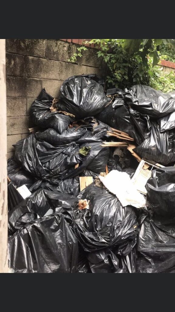 A large pile of black trash bags and wooden debris awaiting removal by Sankofa Clean Outs & Junk Removal in Philadelphia, PA.