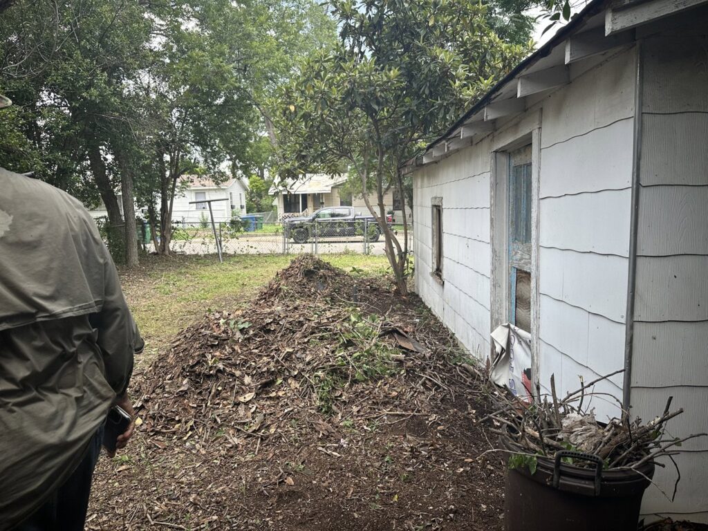 A large pile of leaves and branches in a backyard ready for yard waste removal by Silverhull Junk Removal in San Antonio, TX.