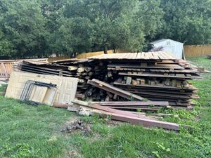 A large pile of wood and construction debris in a backyard, ready for removal by 2 Bald Guys Hauling & Junk Removal in San Antonio, TX.