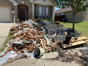 A large pile of wood debris and construction waste on a residential driveway, ready for removal by Epic Junk Removal SD in San Diego, CA.