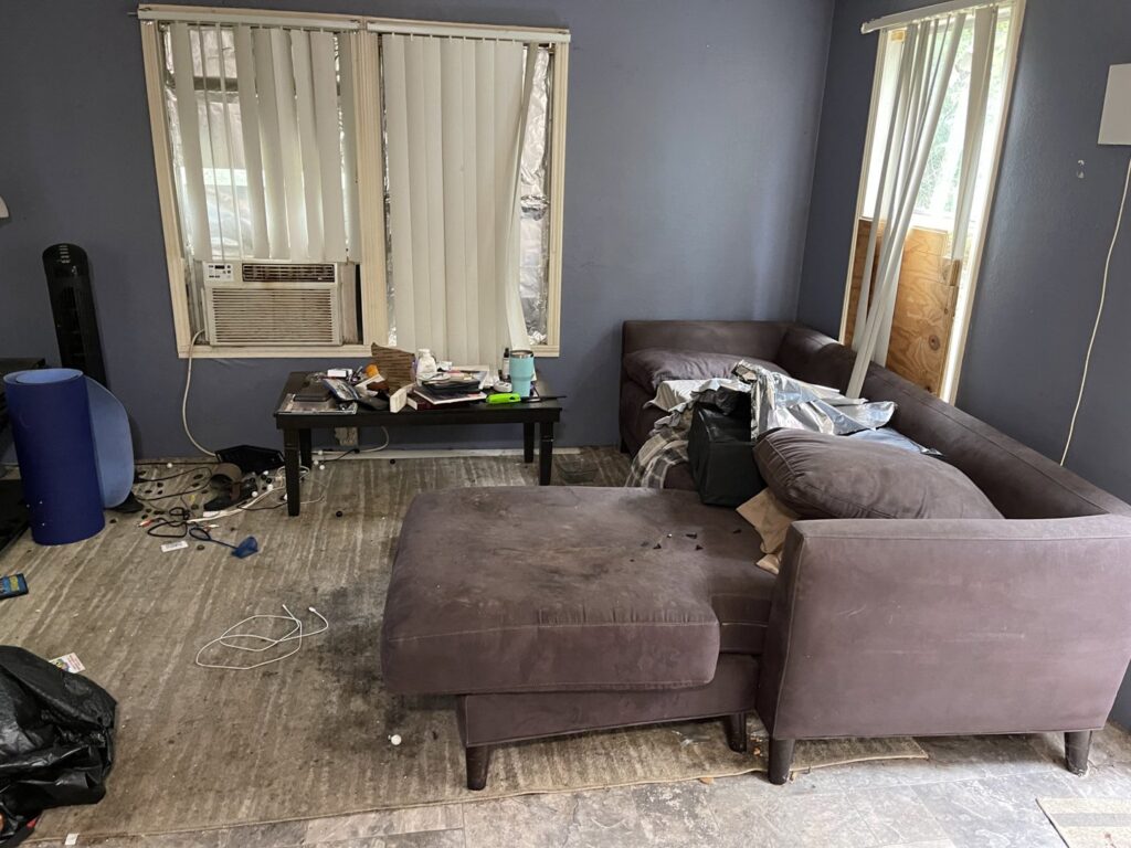 A messy living room with old furniture and clutter, indicating a cleanout and junk removal job by G.I. HAUL in Austin, TX.