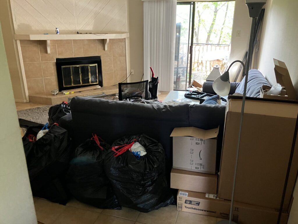 A living room with black trash bags and cardboard boxes piled up, ready for removal by Junkie 4 Jesus Junk Removal in Austin, TX