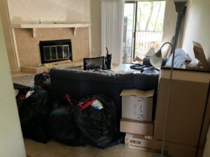 A living room with black trash bags and cardboard boxes piled up, ready for removal by Junkie 4 Jesus Junk Removal in Austin, TX