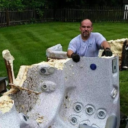 A worker from Joe's Clean Out and Hauling Service LLC removing a broken hot tub in a backyard in Philadelphia, PA.