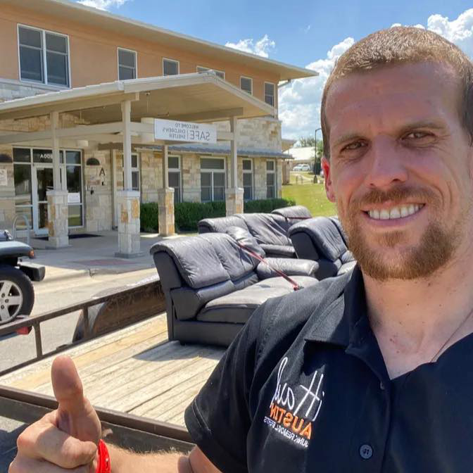 A happy IHaul Austin team member giving a thumbs up after removing two couches in Austin, TX.