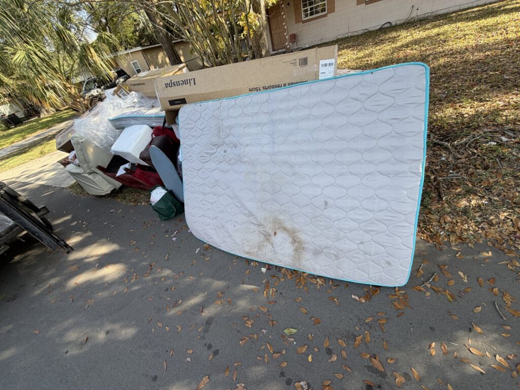 A mattress and other household junk piled on the roadside for pickup by Bring That Junk Removal and Demolition in Jacksonville, FL.