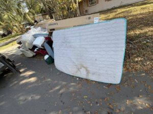 A mattress and other household junk piled on the roadside for pickup by Bring That Junk Removal and Demolition in Jacksonville, FL.
