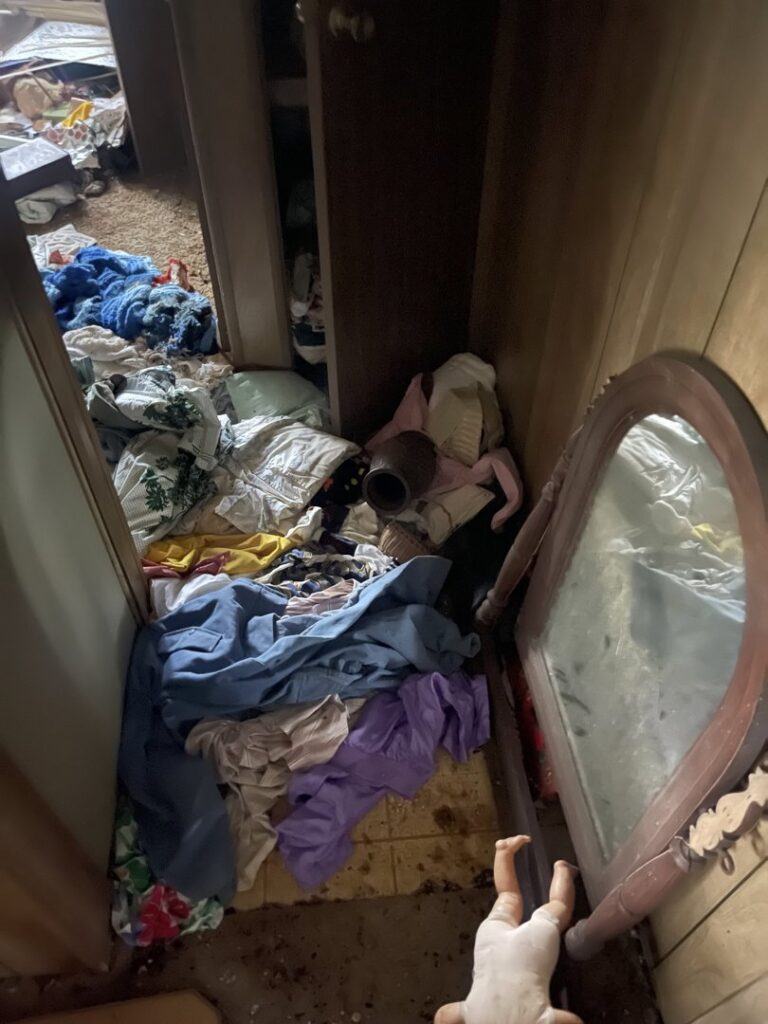 A cluttered room with clothes and various items scattered on the floor, representing a cleanout service by Jacksonville Hauling & Junk Removal in Jacksonville, FL.