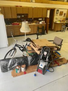 A pile of miscellaneous junk including a bicycle, boxes, and a pressure washer in a workshop, ready for removal by ABC Junk Removal & Hauling in Westfield, IN.